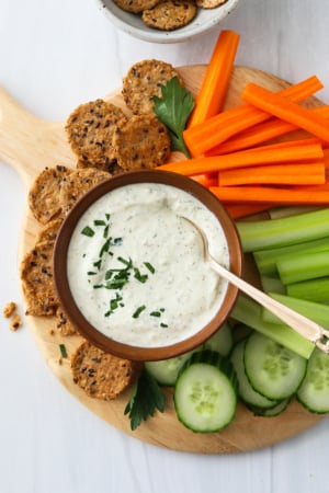 Cottage cheese dip served with sliced veggies and crackers on a platter.