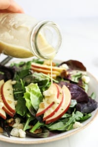 champagne vinaigrette poured over salad from a bottle.
