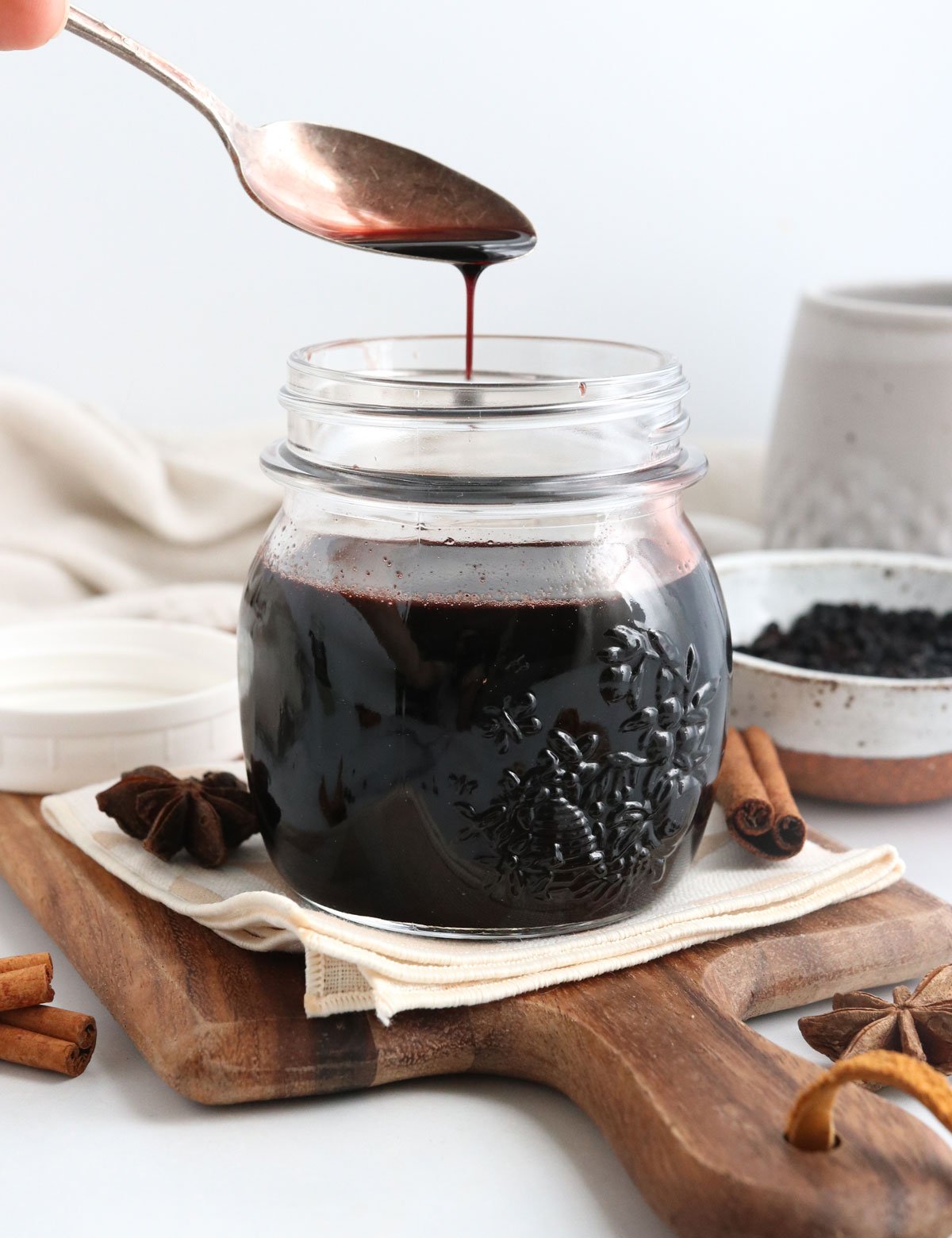 elderberry syrup pouring off of a spoon into jar