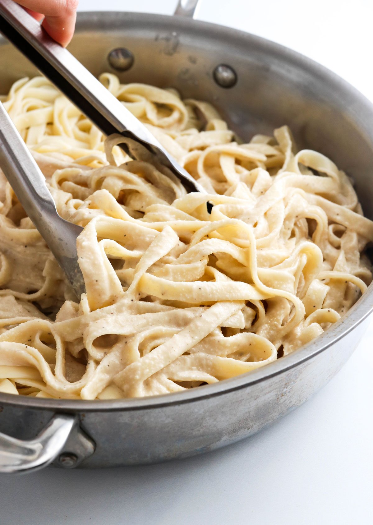 alfredo sauce tossed with pasta in pan